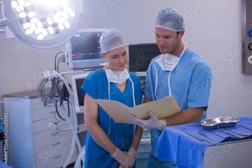 Male and female nurse having discussion over file 