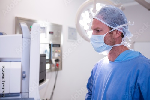 Male surgeon looking at machine in operation theater