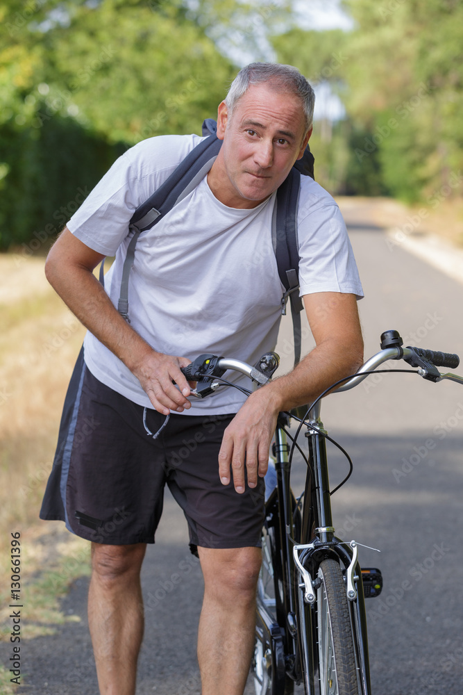 mature man cyclist next to a bicycle