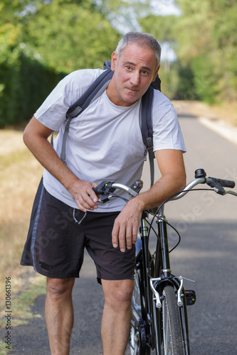 mature man cyclist next to a bicycle © auremar