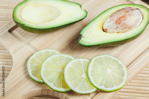 Ripe avocado and lime slices on a wooden background