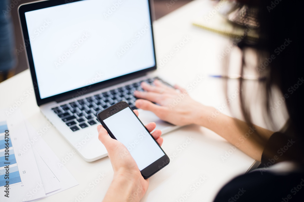 Woman's hands using mobile phone and laptop at the office Woman's hands using mobile phone and laptop at the office