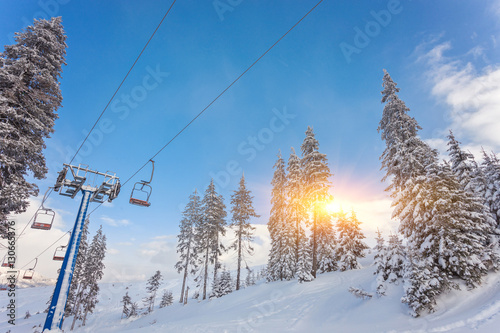 Ski lift with seats going over the mountain and paths from skies photo