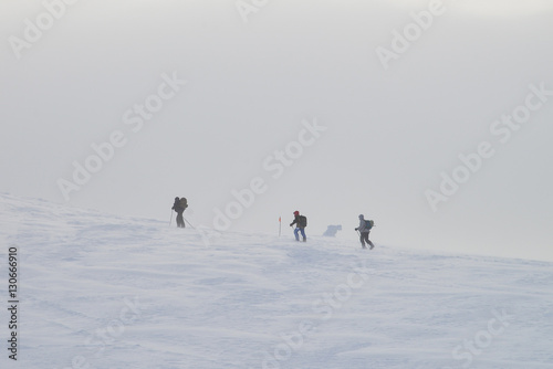 Group of people hiking in winter mountains during a snow storm