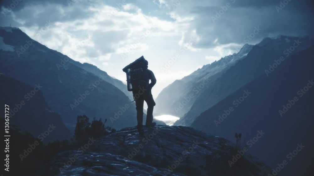 Silhouette of backpacker walking towards the edge of a rocky peak to contemplate the beautiful panorama of the Huascaran National Park. Slow motion