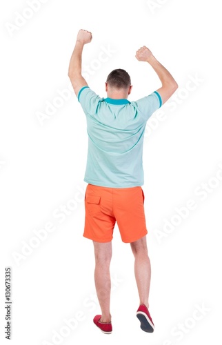 Back view of joyful man celebrating victory hands up.