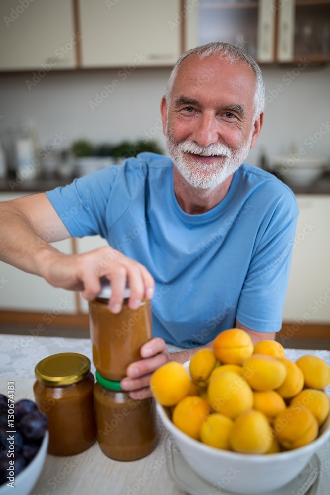 Fototapeta premium Senior man opening bottle of jam
