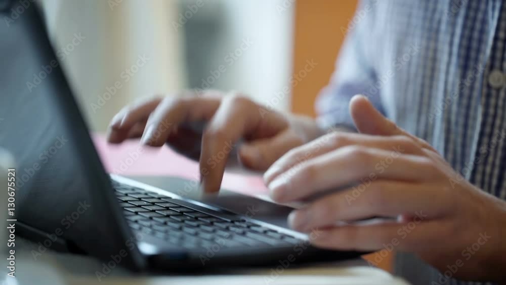 Man sitting by the table and touching button on the laptop's keyboard
Man sitting by the table and touching button on the laptop's keyboard