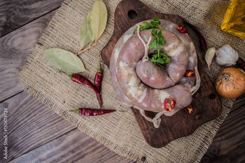 Raw sausage with spices on a dark wooden background. Top view. Close-up