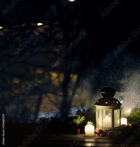 Christmas lantern with snowfall, candles, view from the window on the night street