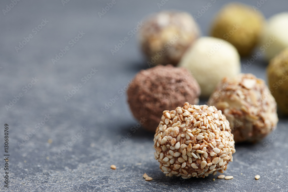 Chocolate truffle candies with sesame seeds and nuts on stone gray background Chocolate truffle candies with sesame seeds and nuts on stone gray background