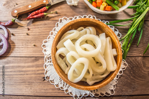 Fresh squid rings and vegetables on a wooden table. top view. Close-up