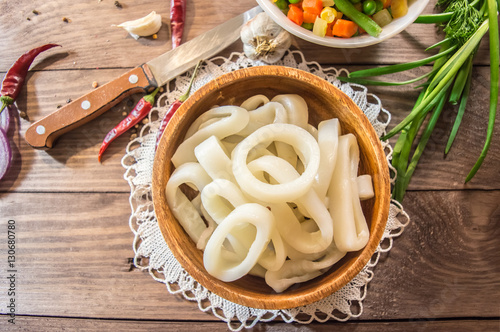 Fresh squid rings and vegetables on a wooden table. top view. Close-up