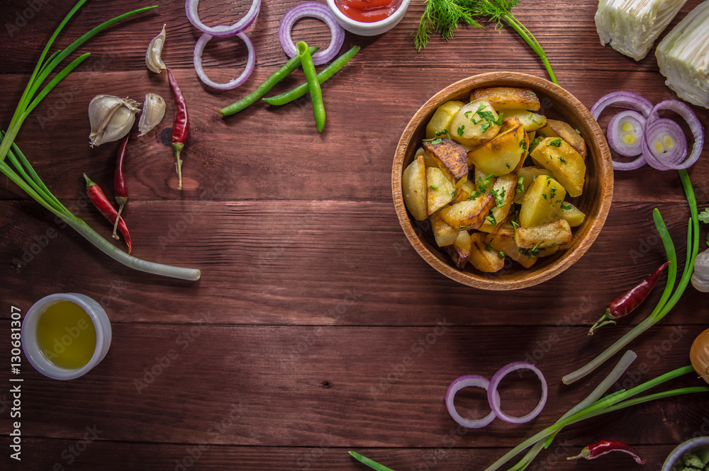 Roasted potatoes with vegetables and herbs on a wooden background, top view. Close-up