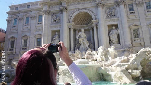 Young woman taking photo of amazing Poli Palace and Trevi fountain in Rome