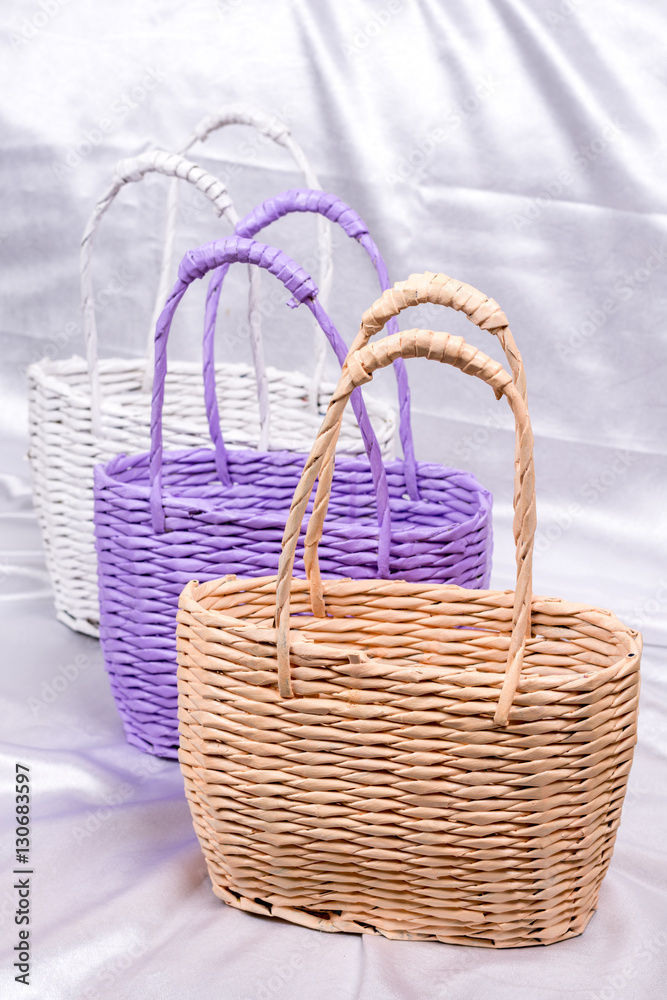 Woven rustic paper basket on white satin