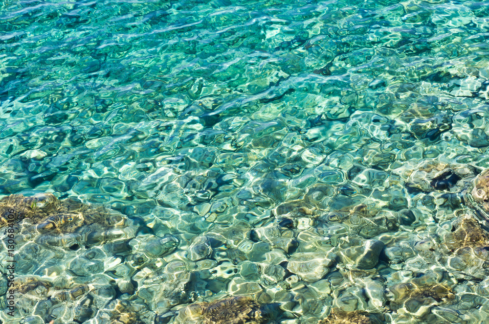 Rocky sea floor visible thru crystal clear turqoise water of Aegean sea in Greece