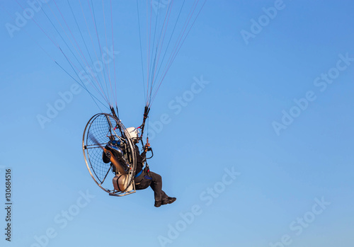 paraglider flying with paramotor on  blue sky  background