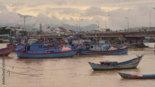 Vietnamese boats on a river at sunset. Busy bridge with lots of motorbikes. Nha Trang, Vietnam travel landscape and destinations. photo