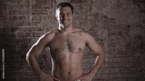 Muscular and fit mature bodybuilder posing demonstrates the core muscles. Isolated on brick background.