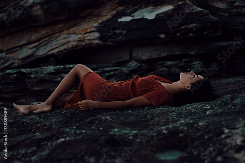 Young woman laying on rocks in the evening light