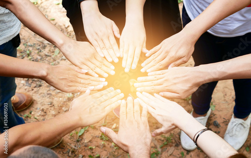 Posting back hand to the center of group of people in circle to photo