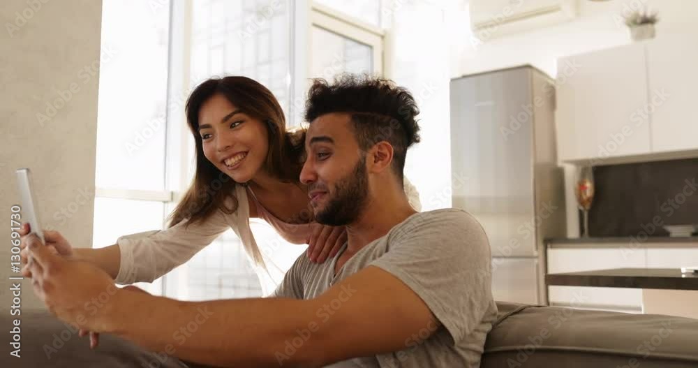 Young Mixed Race Couple Happy Hispanic Man Sit On Coach Asian Woman Using Tablet Computer Together Slow Motion Young Mixed Race Couple Happy Hispanic Man Sit On Coach Asian Woman Using Tablet Computer Together Slow Motion