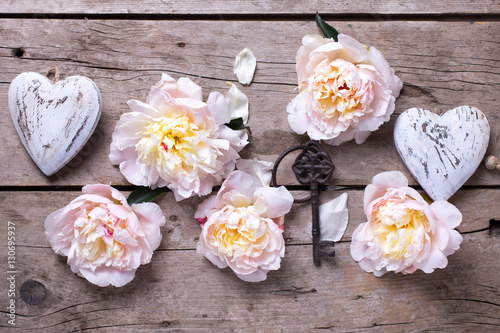 Decorative hearts , key and  pink peonies flowers on aged wooden