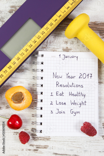 Electronic bathroom scale and new year resolutions written in notebook