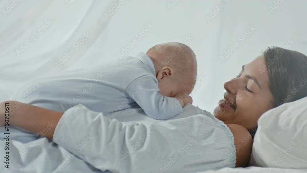 Happy young mother talking to little baby lying on her chest Happy young mother talking to little baby lying on her chest