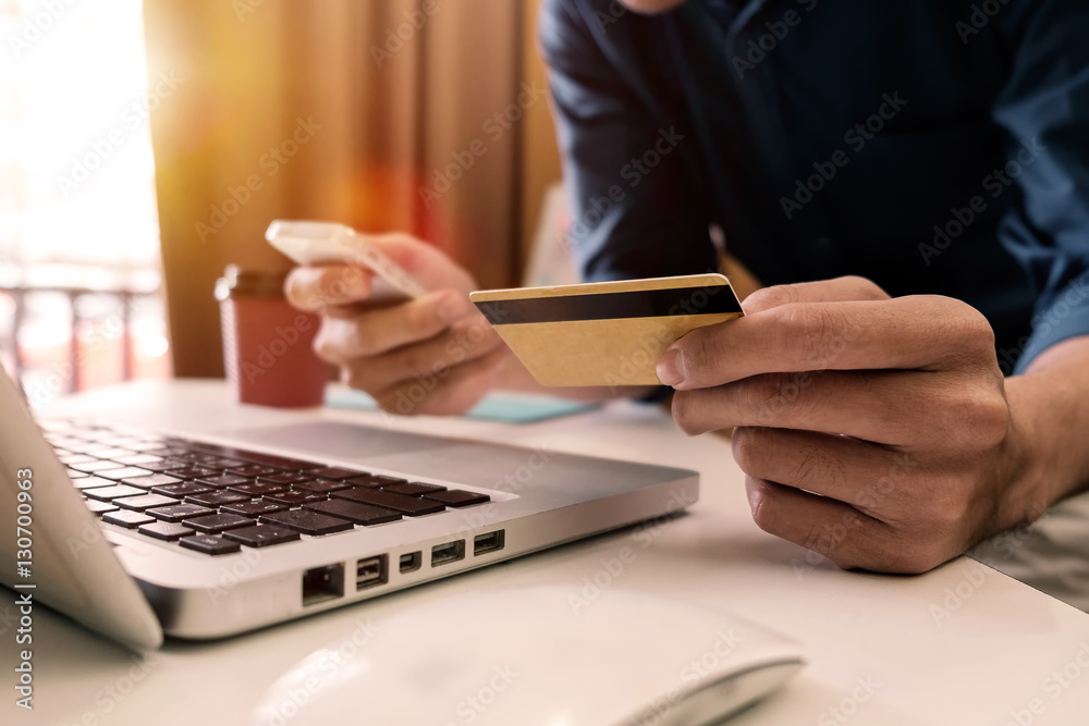 Fototapeta premium Man hands using smartphone laptop and holding credit card with social media as Online shopping concept in morning light 