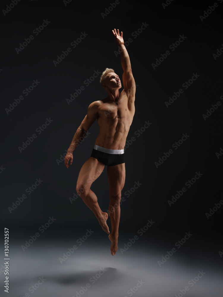 Sexy male gymnast straightening gracefully body up
