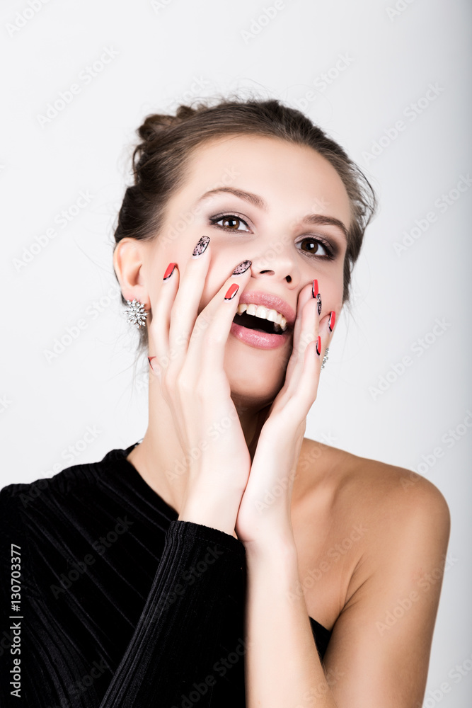Portrait of the young woman in a black dress, holding hands near the face, she surprised Portrait of the young woman in a black dress, holding hands near the face, she surprised