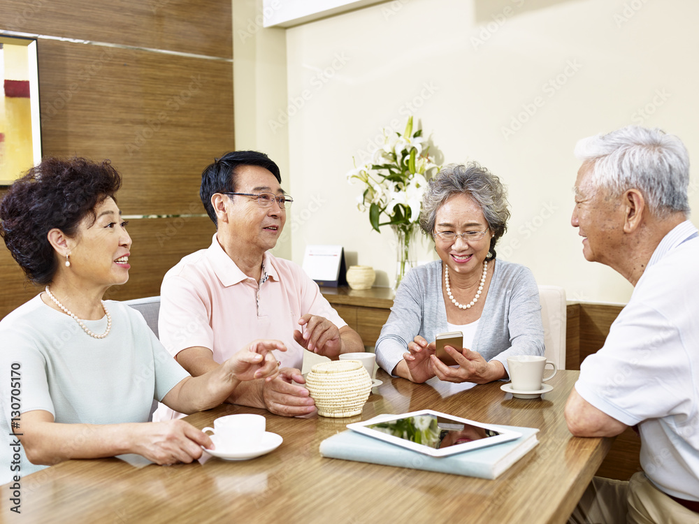 two senior asian couples sitting by table chatting two senior asian couples sitting by table chatting
