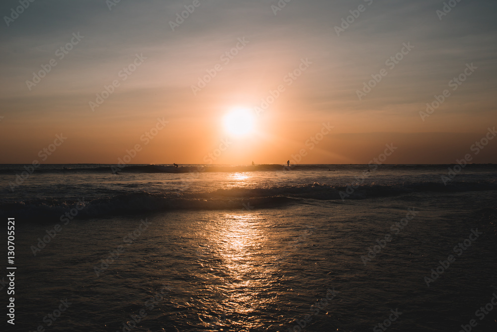 Sunset on the beach of Indian ocean with surfers, Indonesia, Bali