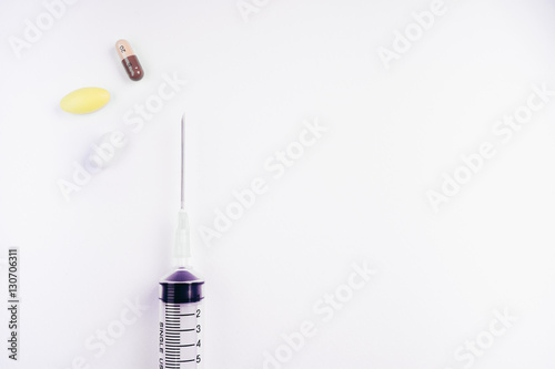 Medication in tablets and capsules and insulin syringe on white background,Empty syringe