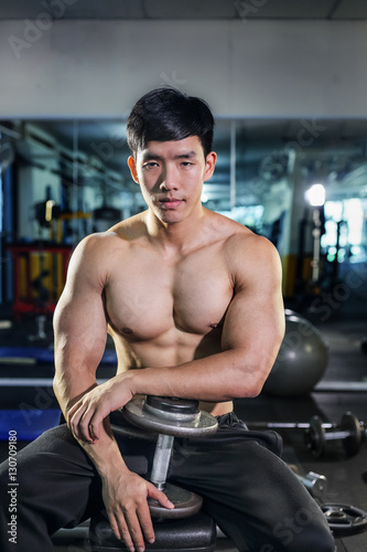 Handsome asian man with dumbbell in the gym