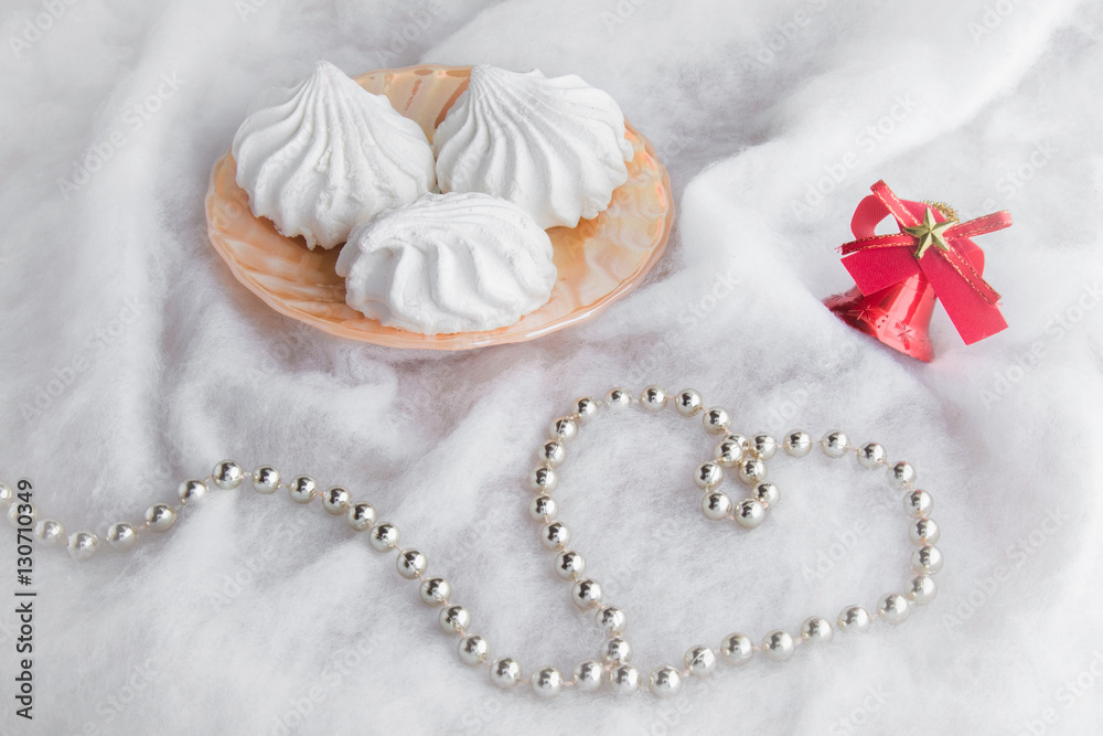 White airy zephyrs in the dish on the soft cloth with a little decorative Christmas bell and small balls chain. Very beautiful surprise for someone in special moment.. Romance. Focus on the zephyrs. White airy zephyrs in the dish on the soft cloth with a little decorative Christmas bell and small balls chain. Very beautiful surprise for someone in special moment.. Romance. Focus on the zephyrs.