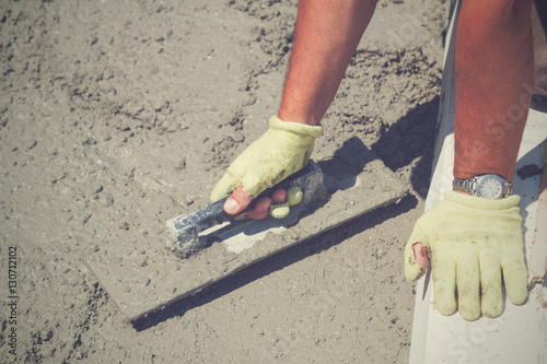 Construction worker leveling concrete pavement.