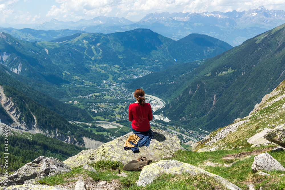 Woman sits on the top on the mountain, Montblanc, exciting the view