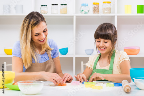 Happy mother and her daughter are making cookie together.