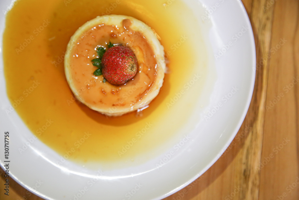 Homemade creme caramel served with sweet syrup and strawberry
