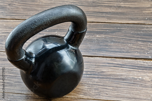 Black kettlebell on wooden background with copyspace. Concept for sport and gym.