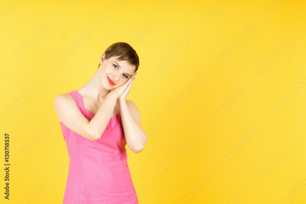 Young woman with short hair  showing emotions and feelings. Isolated on yellow background.