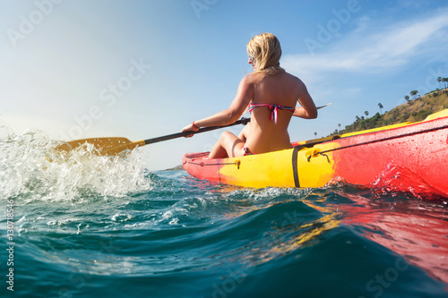 Young woman tourist exploring calm tropical bay  by kayak.