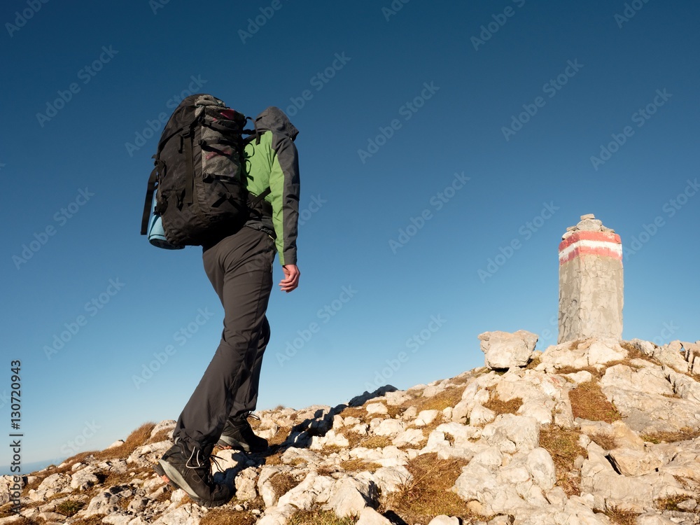 Adult tourist with backpack walk on mountain peak. Last step to summit stone