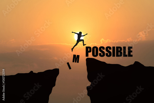 Man jumping over impossible or possible over cliff on sunset background,Business concept idea photo