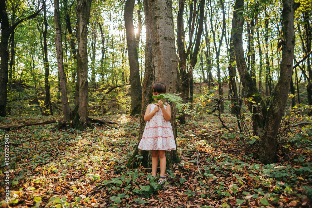 little girl standing in the forest with ferns