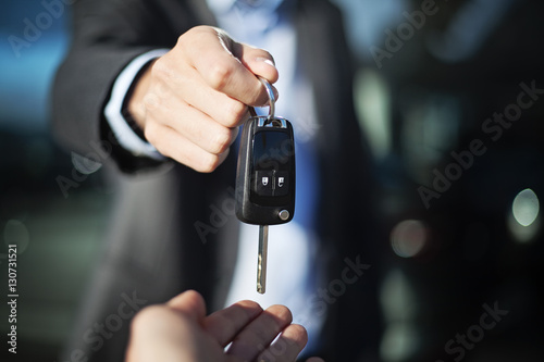 male adult dealer hand giving car keys to female person, close-u