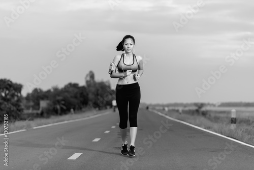 Asian woman running on road in park..